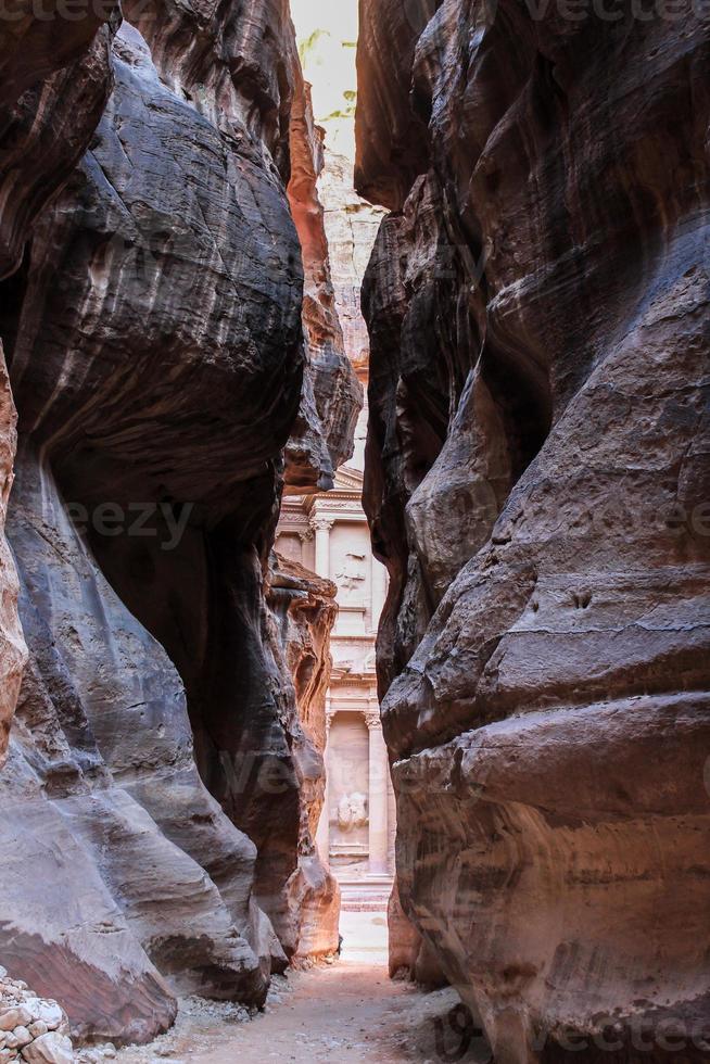 antico nabateo tesoreria lavorato su di roccia, visto attraverso un' crepa nel il rocce a petra foto