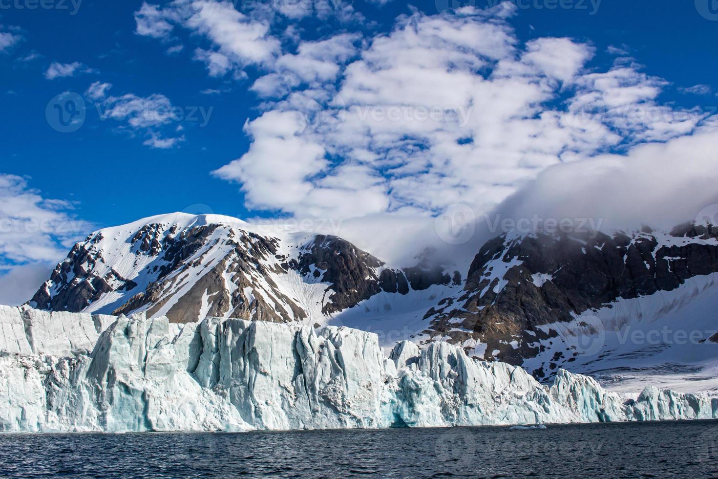 un' ghiacciaio con neve capped montagne dietro a nel svalbard foto