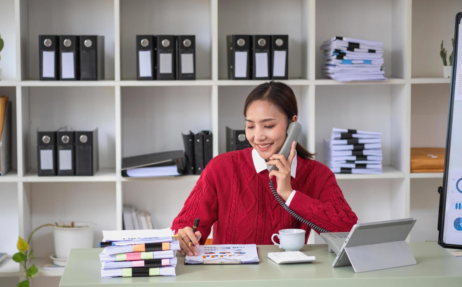 donna d'affari Tenere un' Telefono parlando per sua supervisore e mostrando sua profitto dati nel grafici per sua supervisore utilizzando un' il computer portatile computer. foto