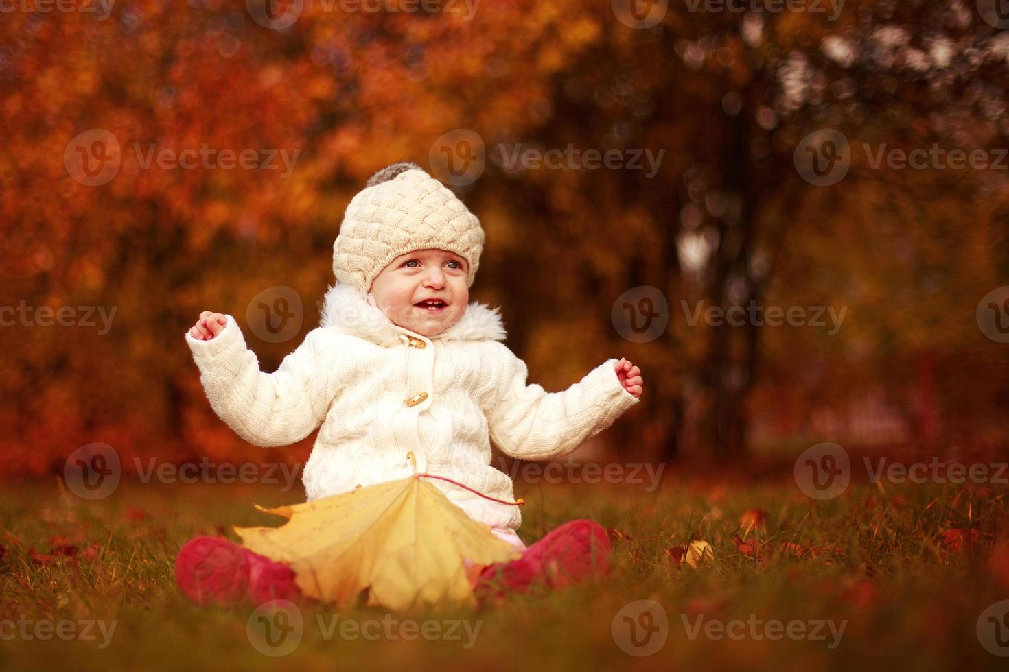 bellissimo poco bambino ragazza seduta con un' grande foglia a autunno parco foto