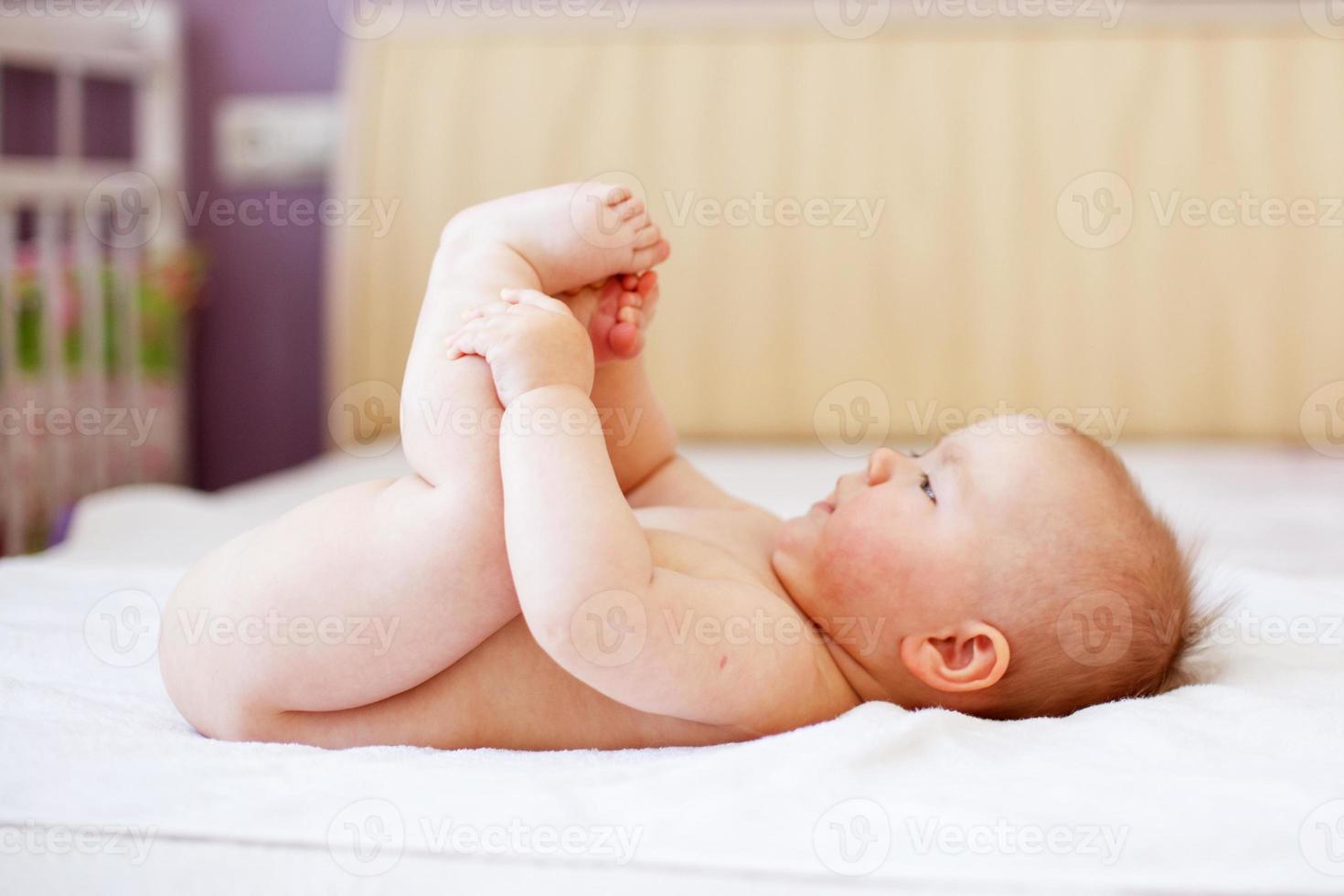 contento bambino giocando con il suo piedi su bianca sfondo. ritratto di un' carino contento bambino foto