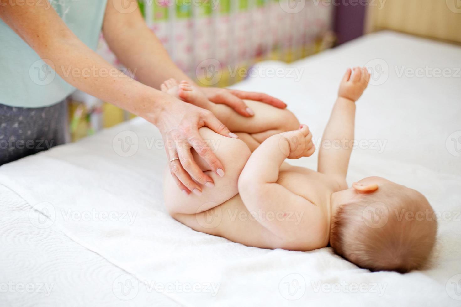 mamma fa ginnastica per un' bambino. madre massaggio bambino nel letto a casa foto