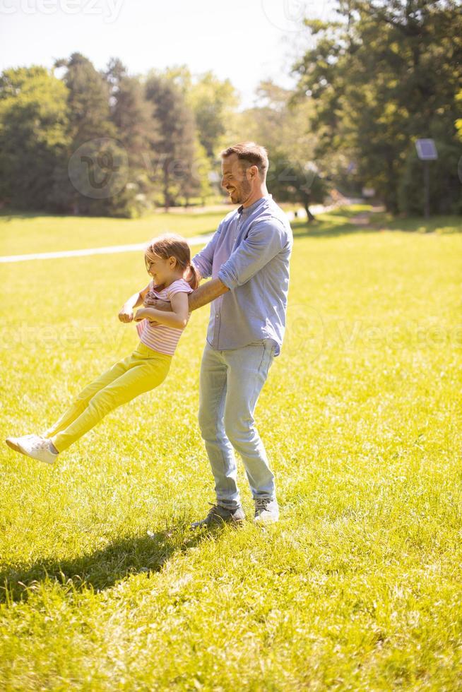 padre con figlia che si diverte sull'erba al parco foto