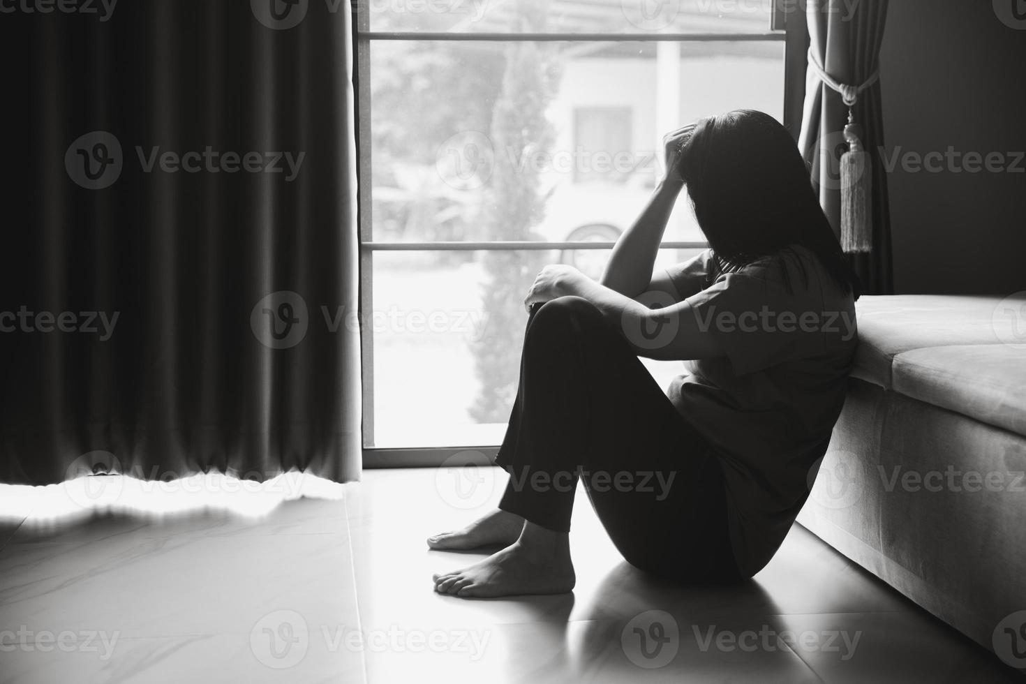 schizofrenia con solitario e triste nel mentale Salute depressione concetto. depresso donna seduta contro pavimento a casa con buio camera sensazione miserabile. donne siamo depresso, pauroso e infelice. foto