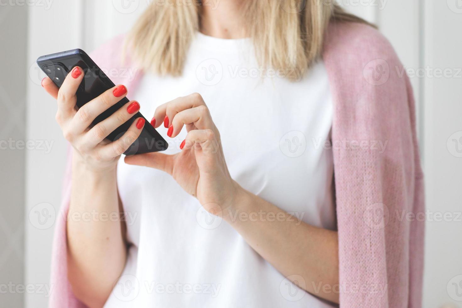 vicino su donna mani con rosso manicure uso un' smartphone su bianca sfondo scrittura testo Messaggio godere in linea comunicazione shopping ordine Prodotto foto