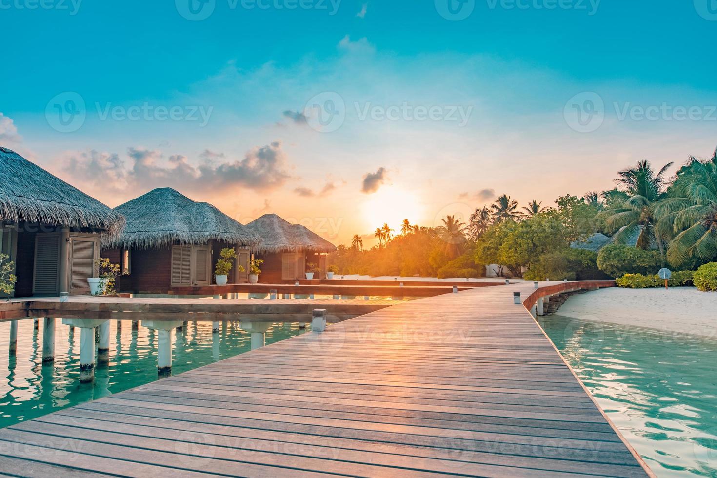 tramonto sull'isola delle maldive, resort di ville sull'acqua di lusso e molo in legno. bel cielo e nuvole e sfondo della spiaggia per le vacanze estive e il concetto di viaggio foto