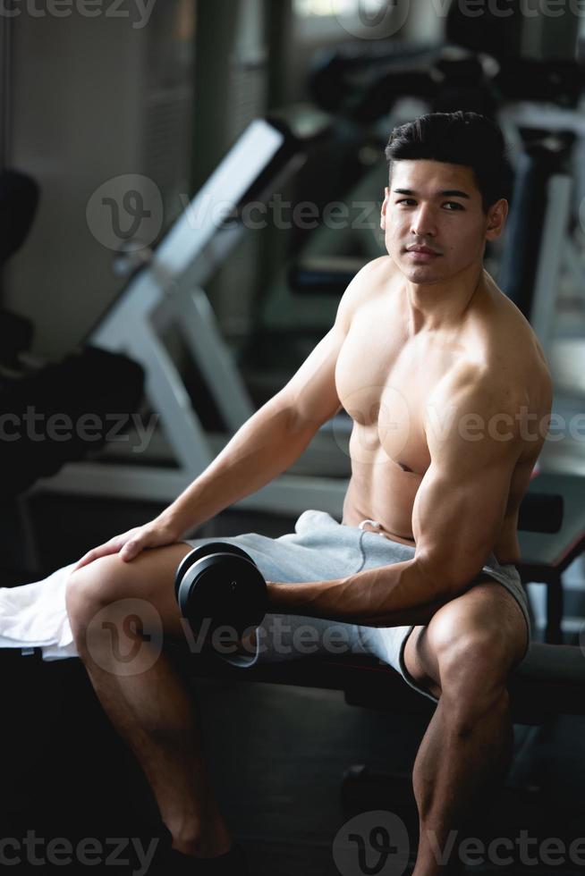 giovane uomo allenamento, sollevamento con manubrio per costruire muscolo nel fitness a palestra. foto