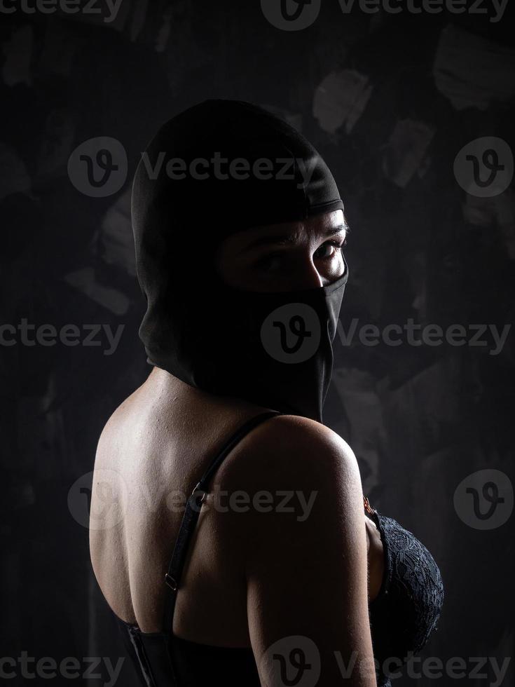 ritratto di un' ragazza nel un' nero Balaclava e un' nero reggiseno. foto