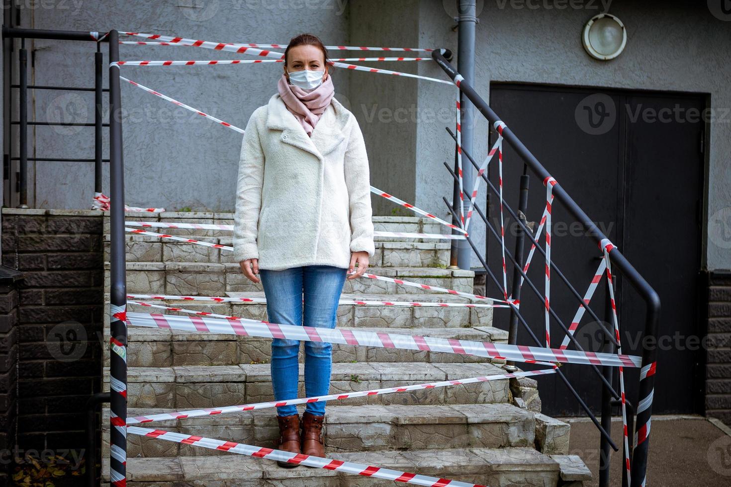 foto di una ragazza in maschera. in piedi per strada con nastri di avvertimento di pericolo.