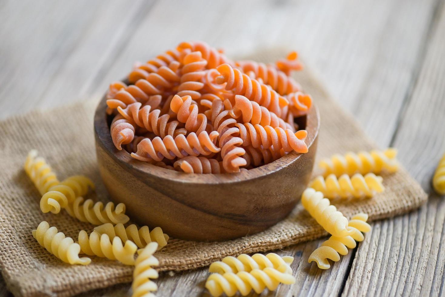 pasta crudo maccheroni su di legno ciotola sfondo, vicino su crudo maccheroni spirale pasta crudo delizioso totale grano fusilli pasta per cucinando cibo foto