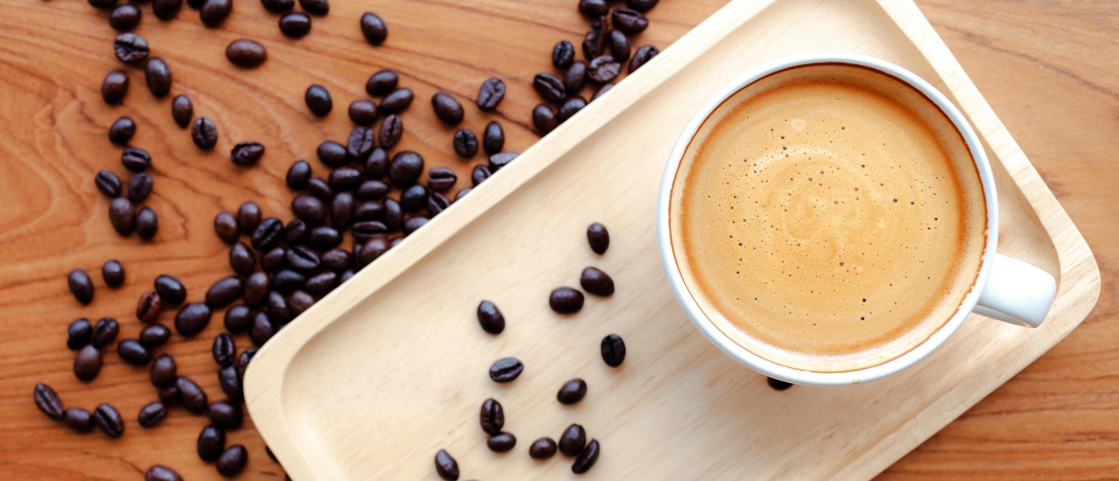 superiore Visualizza di il bianca tazza di caffè espresso caffè e arrostito caffè fagioli su di legno sfondo foto