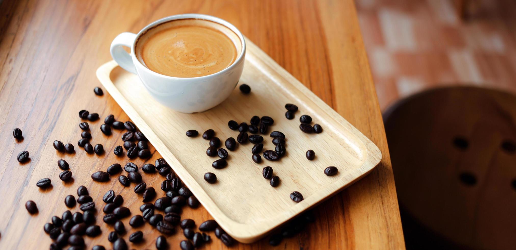 bianca tazza di caffè espresso caffè e arrostito caffè fagioli su di legno contatore a caffè negozio foto