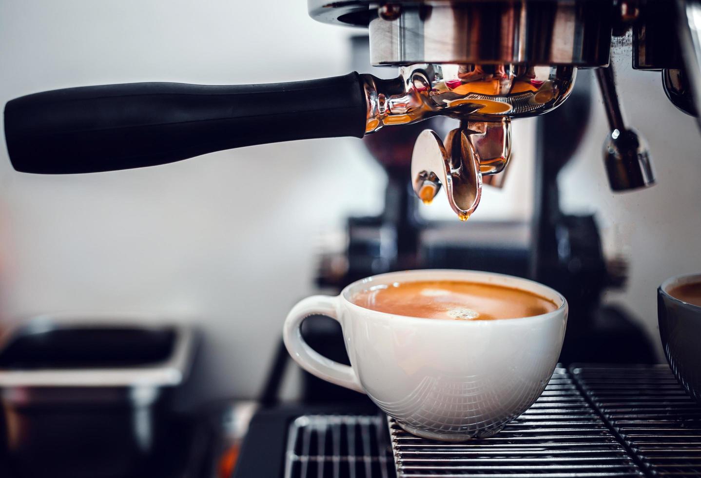 caffè estrazione a partire dal il caffè macchina con un' portafilter scrosciante caffè in un' tazza, espresso poro a partire dal caffè macchina a caffè negozio foto