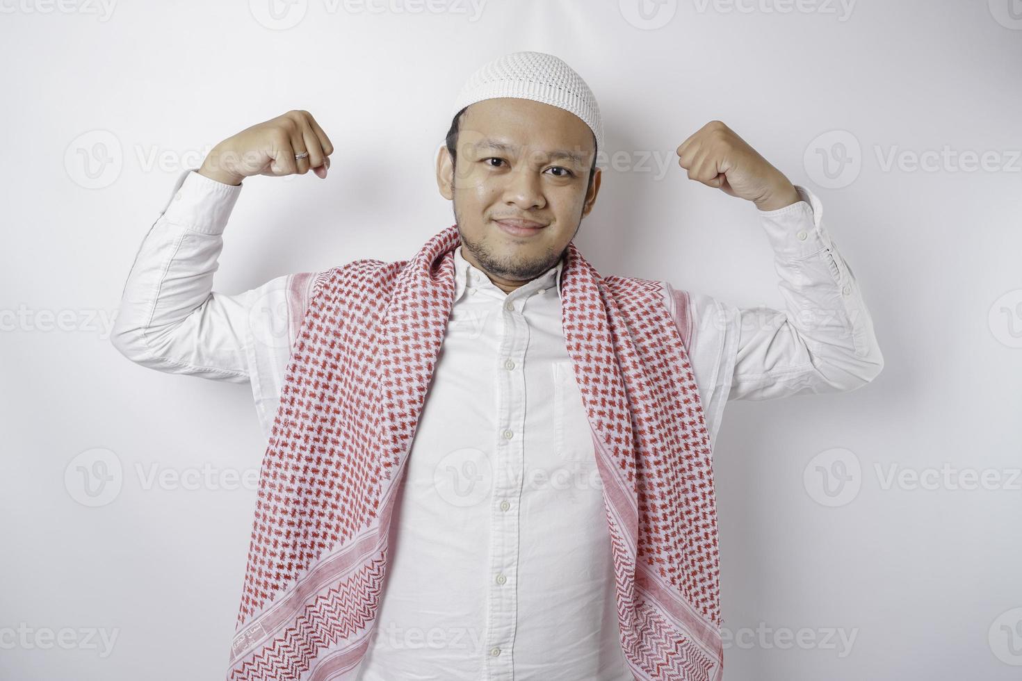 eccitato asiatico musulmano uomo mostrando forte gesto di sollevamento il suo braccia e muscoli sorridente con orgoglio foto