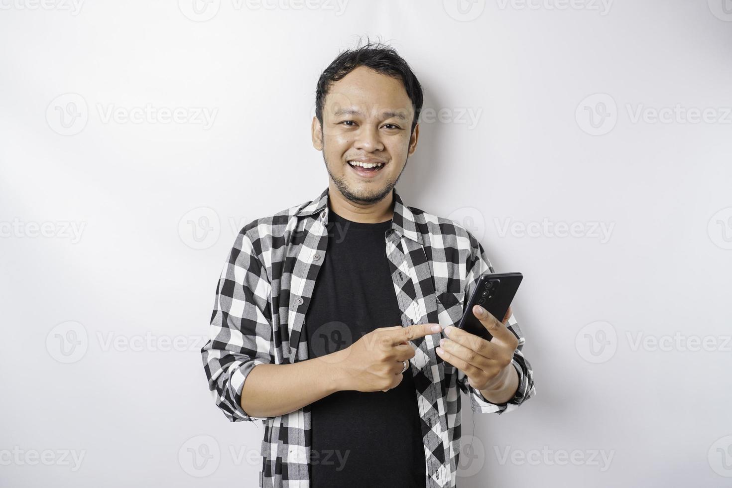 un' ritratto di un' contento asiatico uomo è sorridente mentre Tenere su il suo Telefono, isolato di bianca sfondo foto