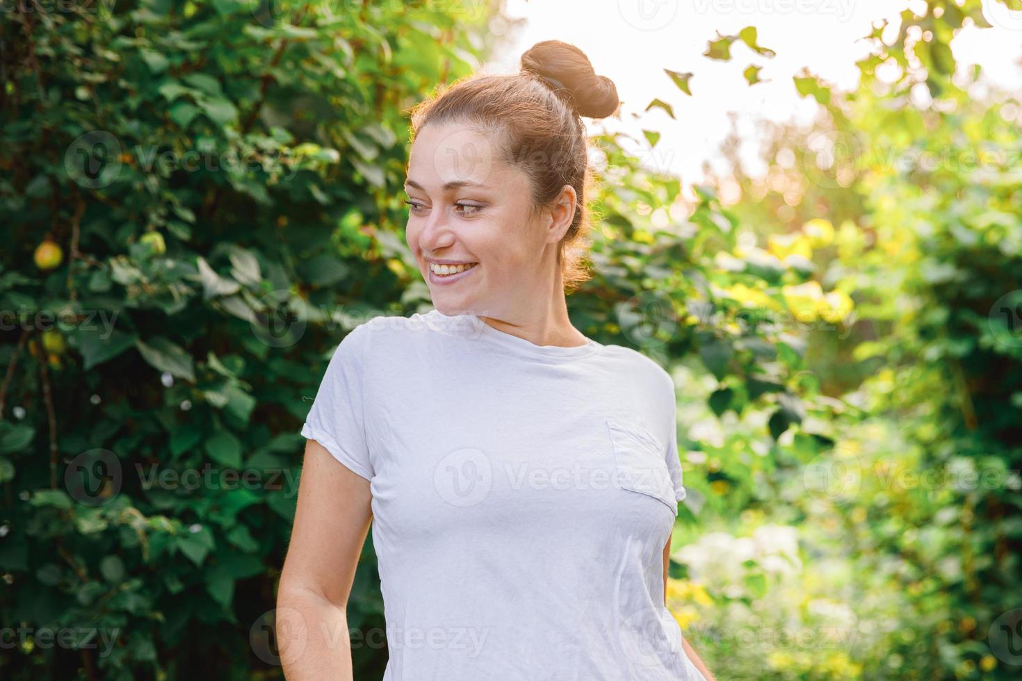 giovane donna sorridente all'aperto. bellissimo bruna ragazza riposo su parco o giardino verde sfondo. gratuito contento donna a estate. la libertà felicità spensierato contento persone concetto. foto