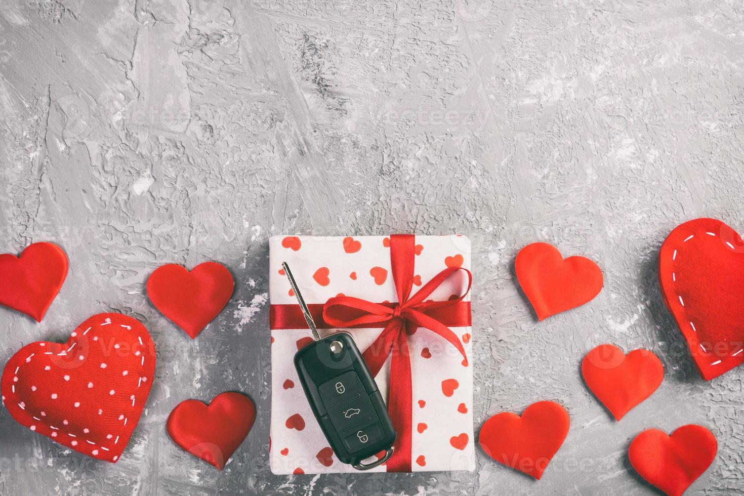 San Valentino o altro vacanza fatto a mano presente nel carta con rosso cuori, auto chiavi e i regali scatola nel vacanza involucro. scatola regalo su grigio cemento tavolo superiore Visualizza con copia spazio, vuoto spazio per design foto