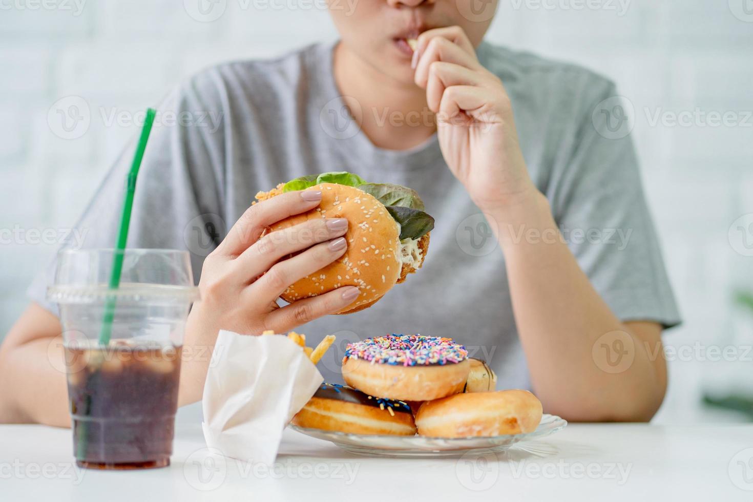 donna mangiare veloce cibo hamburger, licenziato pollo , ciambelle e dolci foto