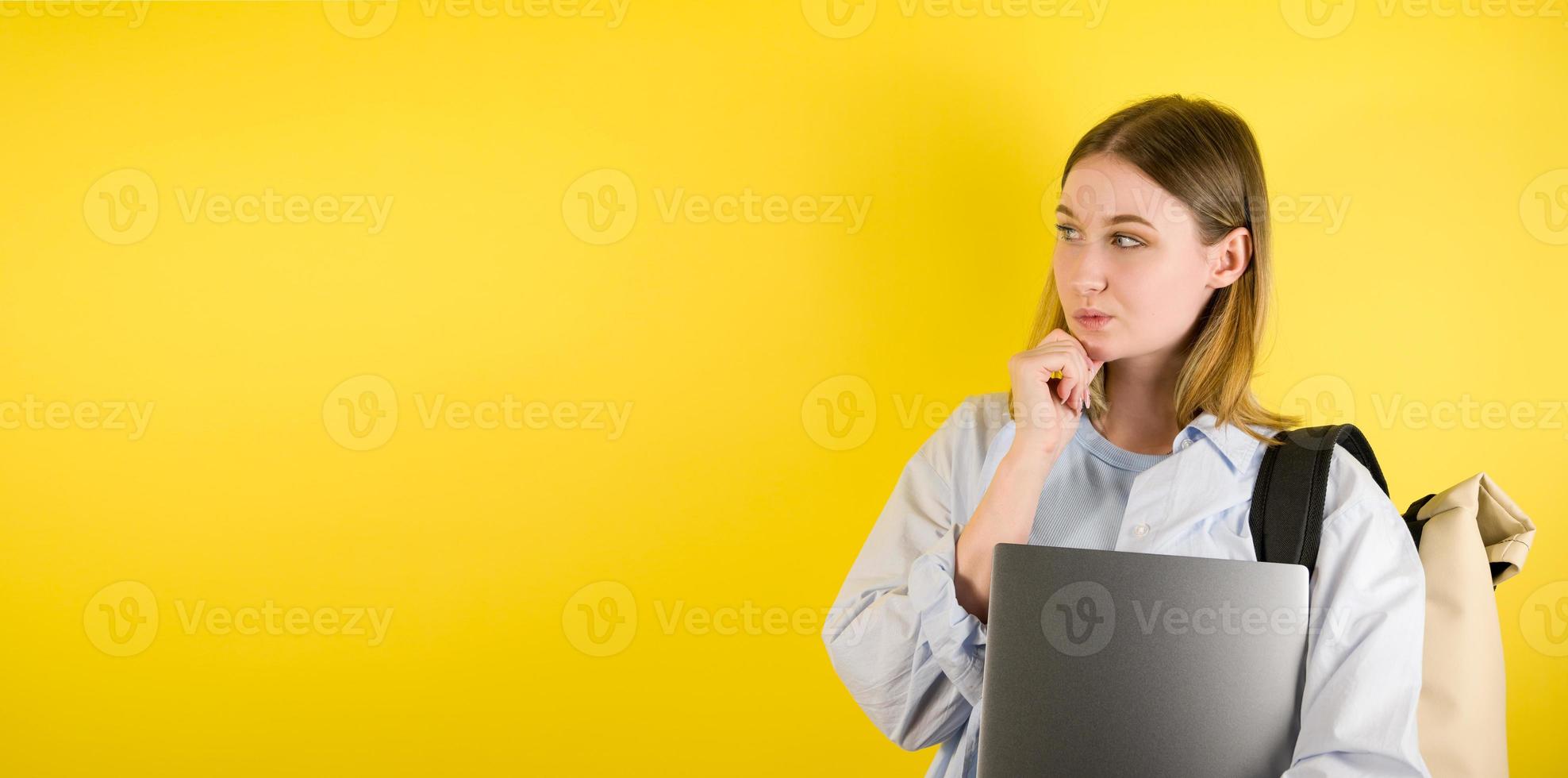 ritratto di pensiero giovane femmina con il computer portatile con confuso perplesso viso su giallo isolato sfondo. studio tiro .copyspace bandiera foto