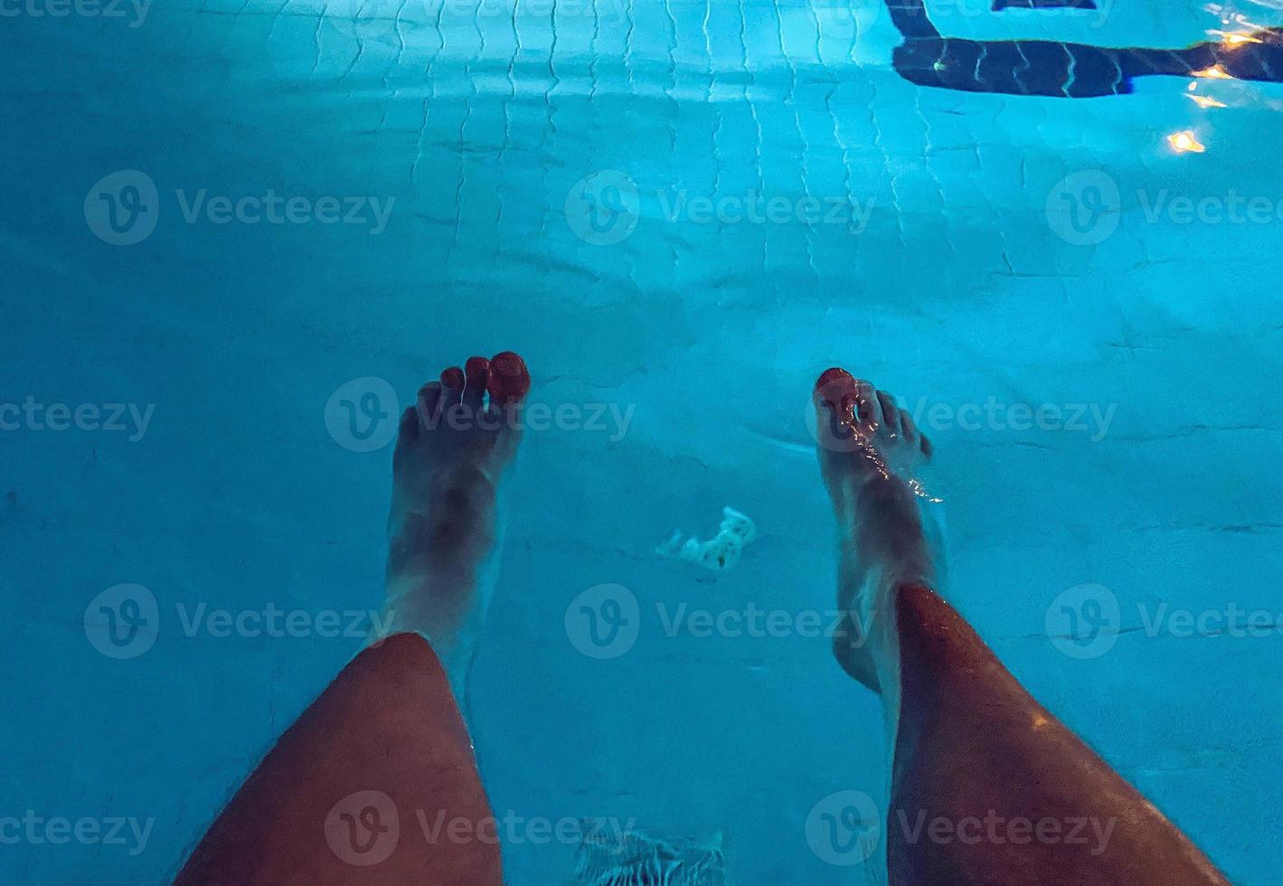 vacanza a mare su il spiaggia. bianca maschio gambe. piscina con turchese, clorurato acqua, a il parte inferiore di il grattugiare per acqua purificazione foto