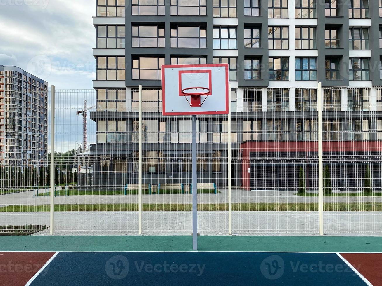 pallacanestro cestino e tavola su il gli sport terra nel il città cortile vicino il nuovo edificio foto