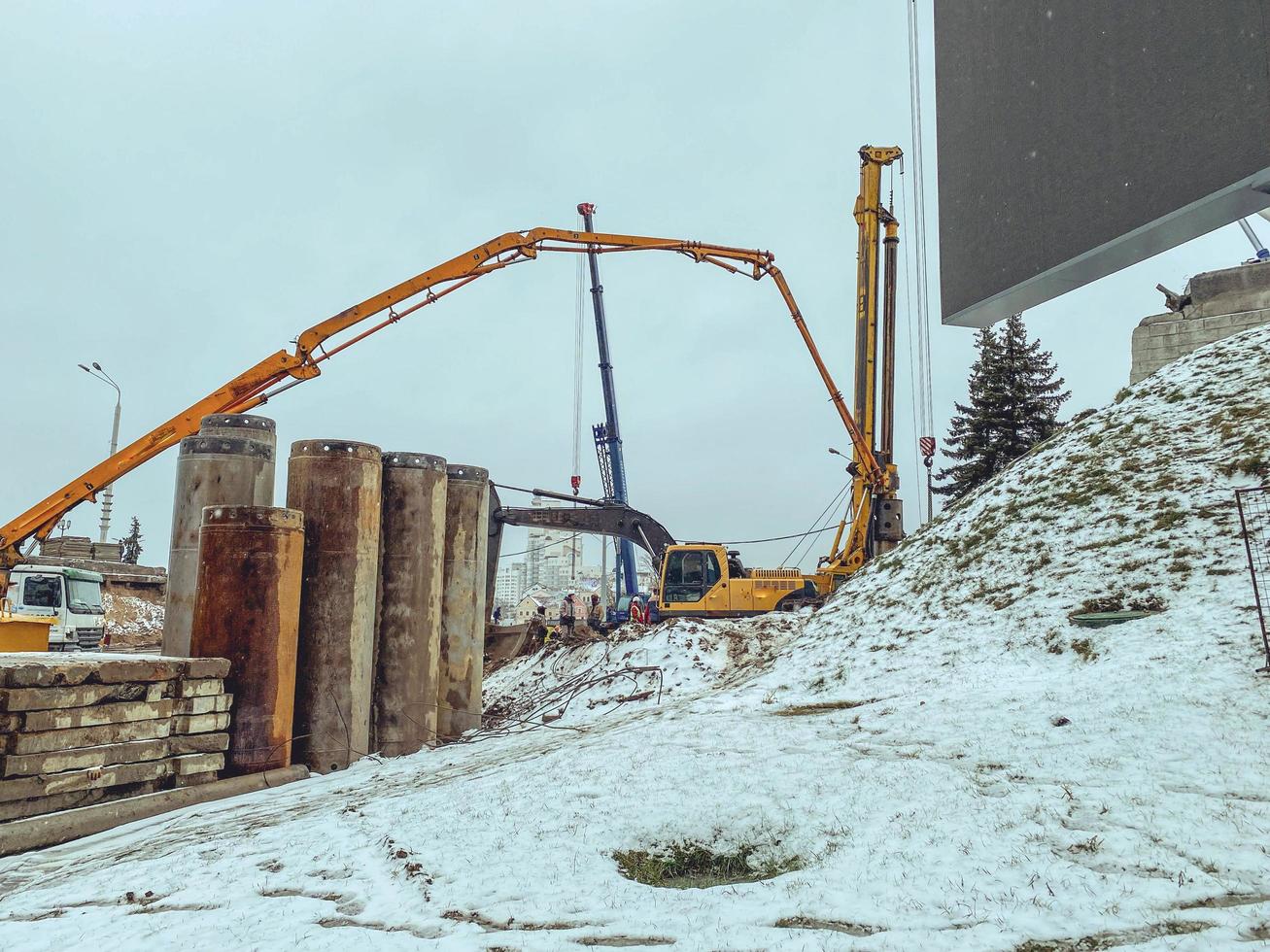 costruzione di un' ponte nel il città centro nel inverno sotto neve. macchine per il costruzione di grande calcestruzzo strutture e barriere foto