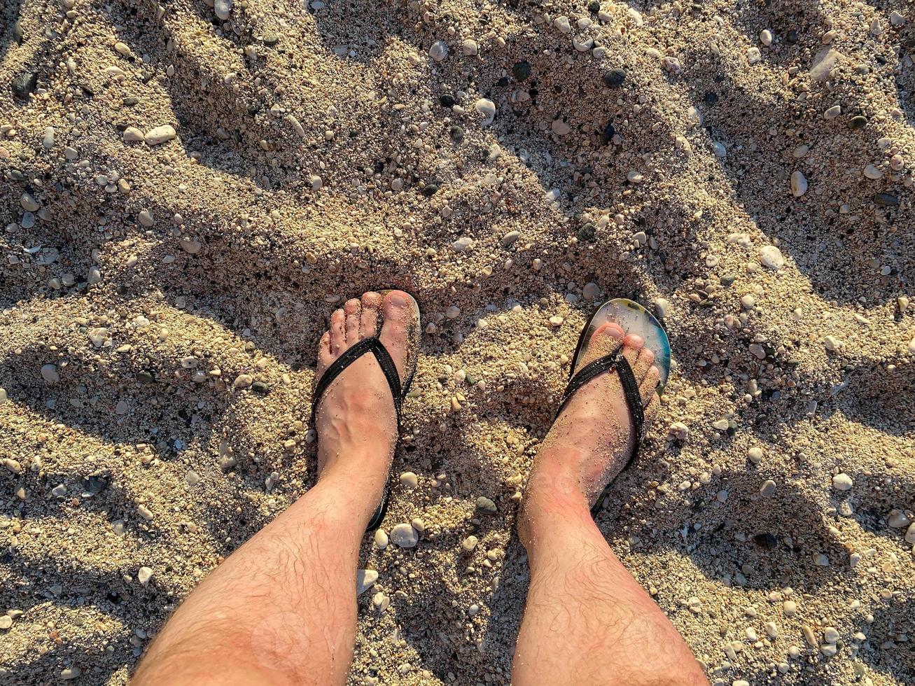 Basso sezione di uomo in piedi su riva a spiaggia foto