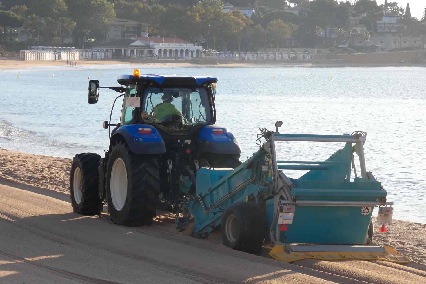 trattore pulizia il bianca sabbia su il spiaggia foto