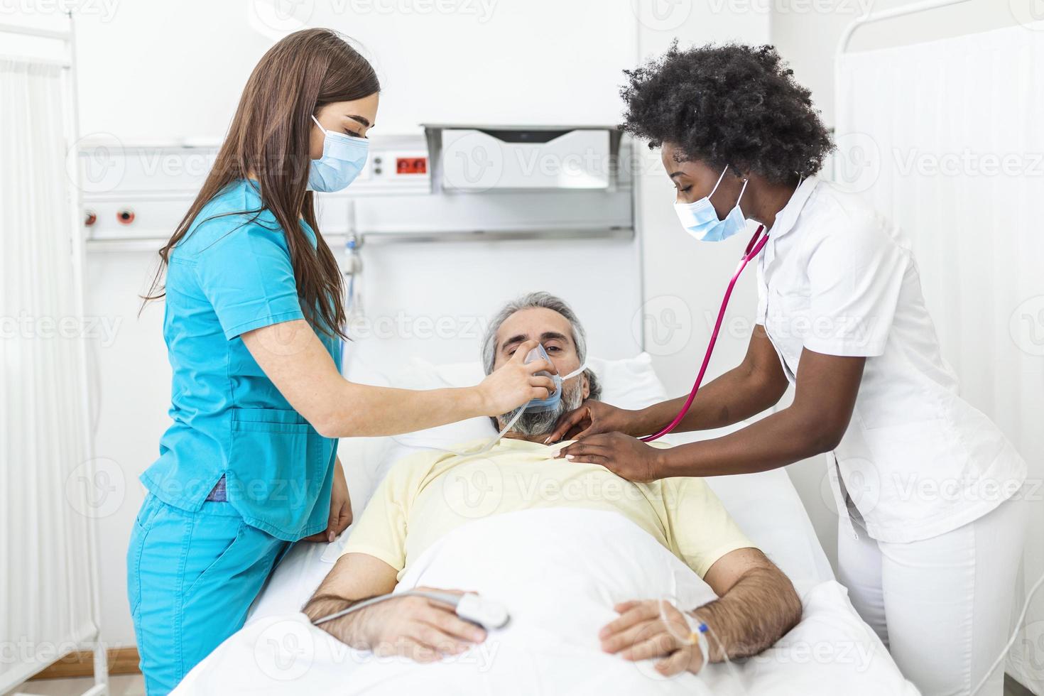 infermiera mette ossigeno maschera su anziano uomo paziente dire bugie nel il ospedale camera letto mentre africano americano medico l'esame paziente con stetoscopio, coronavirus covid 19 protezione concetto foto