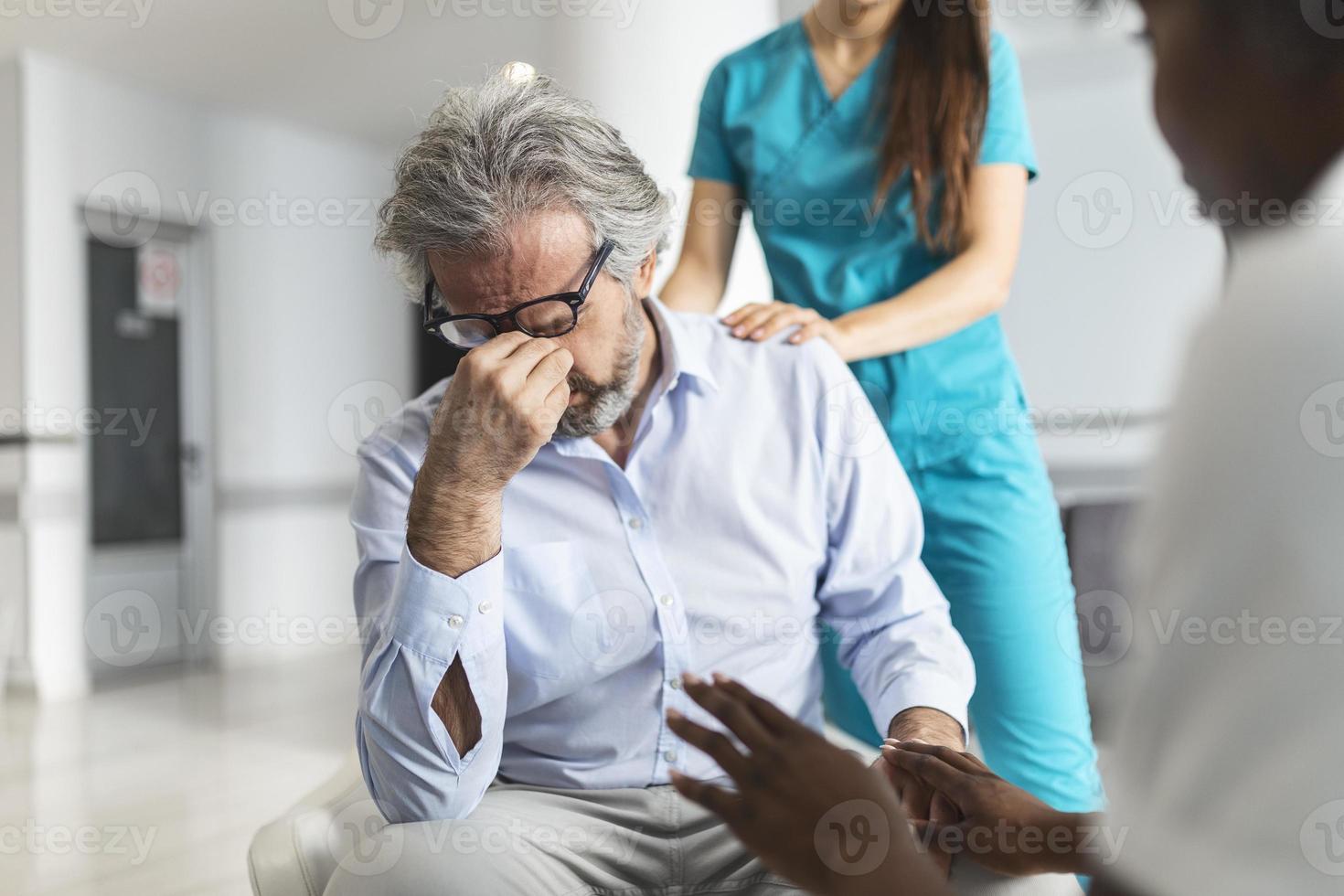 medico consolante irritato uomo nel ospedale in attesa camera. paziente ricevente cattivo notizia, lui è disperato e pianto, medico supporto e confortante sua paziente con simpatia. foto