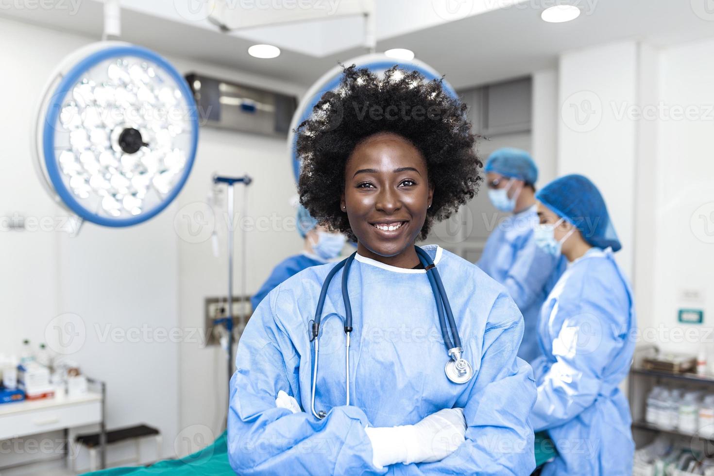 ritratto di contento africano americano donna chirurgo in piedi nel operativo camera, pronto per opera su un' paziente. femmina medico lavoratore nel chirurgico uniforme nel operazione Teatro. foto
