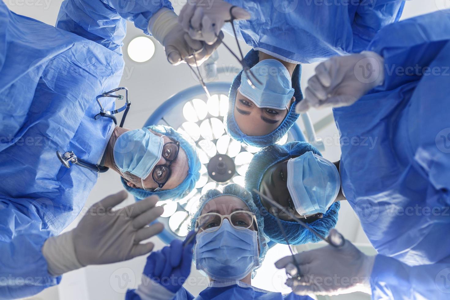 chirurghi in piedi sopra di il paziente prima chirurgia. multietnico assistenza sanitaria lavoratori l'esecuzione chirurgia su paziente a operazione Teatro. foto