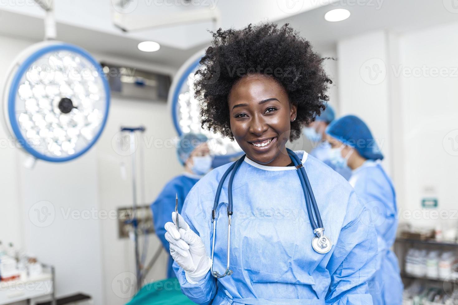 ritratto di sorridente africano americano femmina chirurgo nel chirurgico uniforme Tenere bisturi a operativo camera. giovane donna medico nel ospedale operazione Teatro. foto