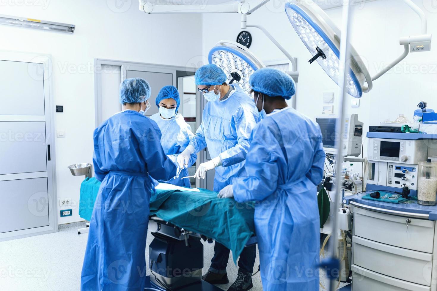 gruppo di medico squadra urgentemente fare chirurgico operazione e porzione paziente nel Teatro a Ospedale. medico squadra l'esecuzione chirurgico operazione nel un' luminosa moderno operativo camera foto