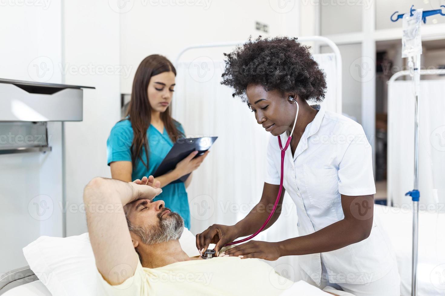 ricoverato in ospedale uomo dire bugie nel letto mentre medico controllo il suo polso. medico e infermiera l'esame anziano maschio paziente nel ospedale camera. foto