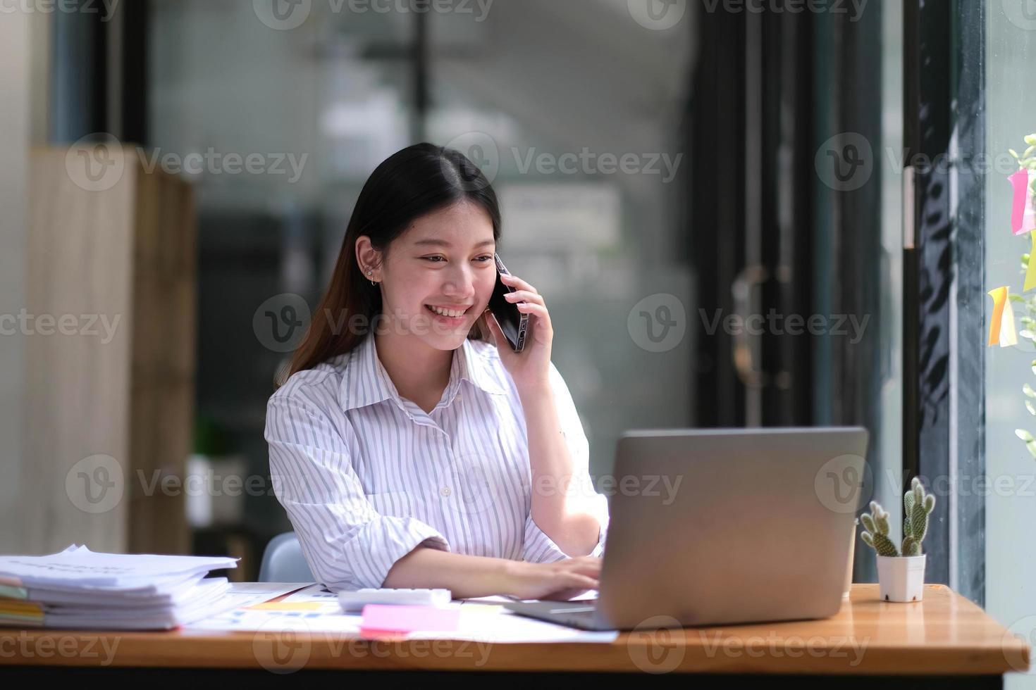 ritratto di giovane donna asiatica d'affari parlare su smartphone scrivere notebook portatile in ufficio a casa. bella ragazza al computer da scrivania portare a casa l'ordine. startup business asia donna online sme telemarketing. foto