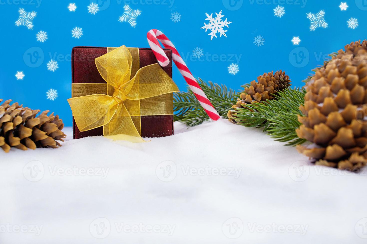 regalo scatola con giallo arco, caramella canna e coni con abete rami su neve. dietro a fiocchi di neve. Natale, nuovo anno. copia spazio foto