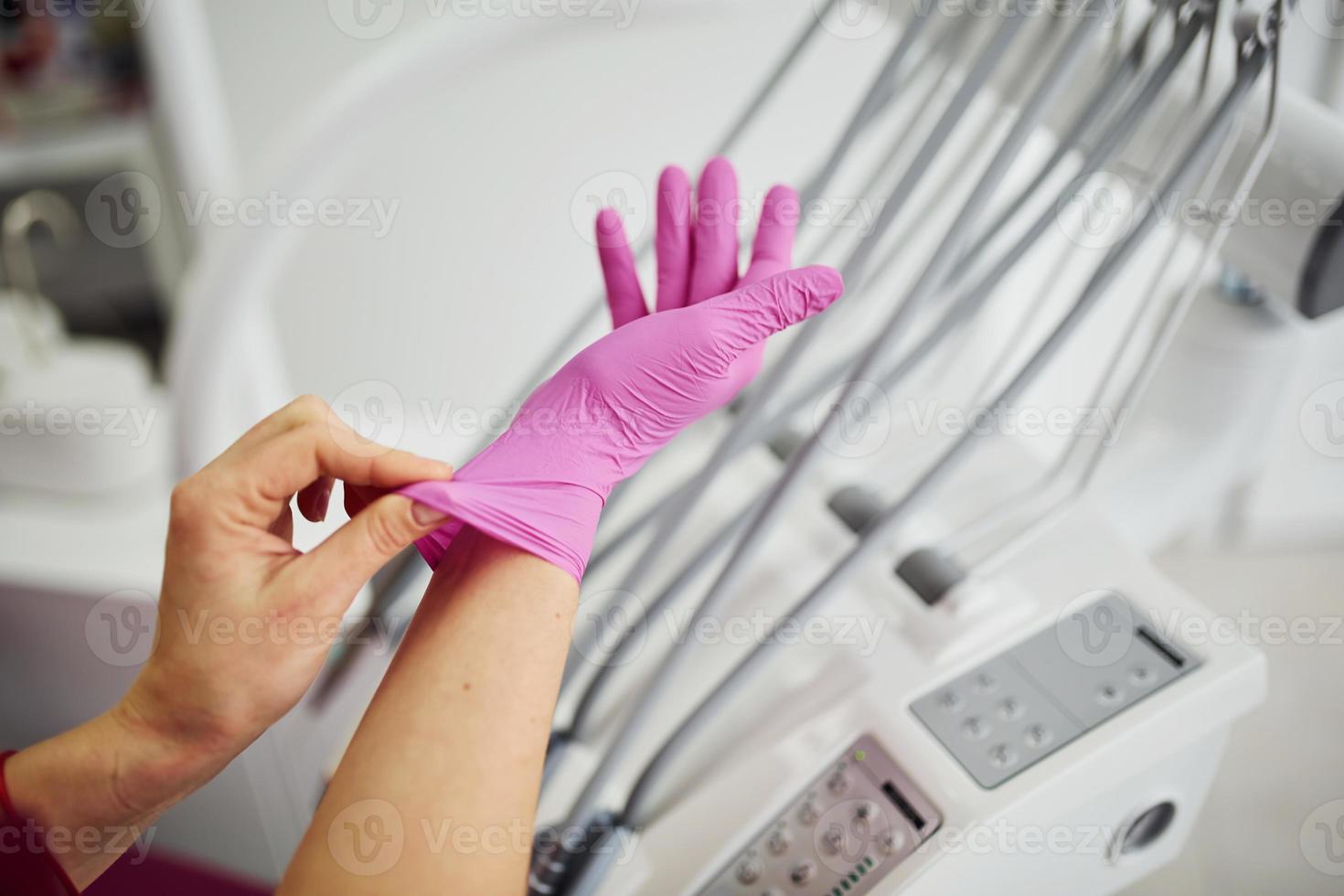 vicino su Visualizza di femmina dentista nel uniforme indossare guanti nel stomatologia ufficio foto