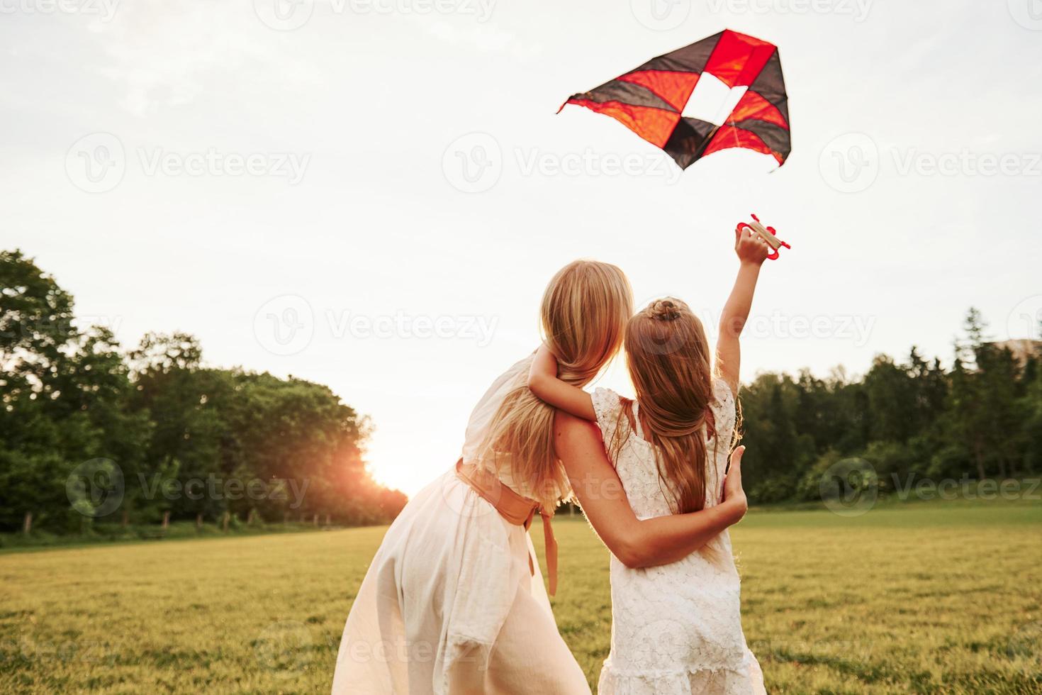 Guardando il cielo. madre e figlia avere divertimento con aquilone nel il campo. bellissimo natura foto