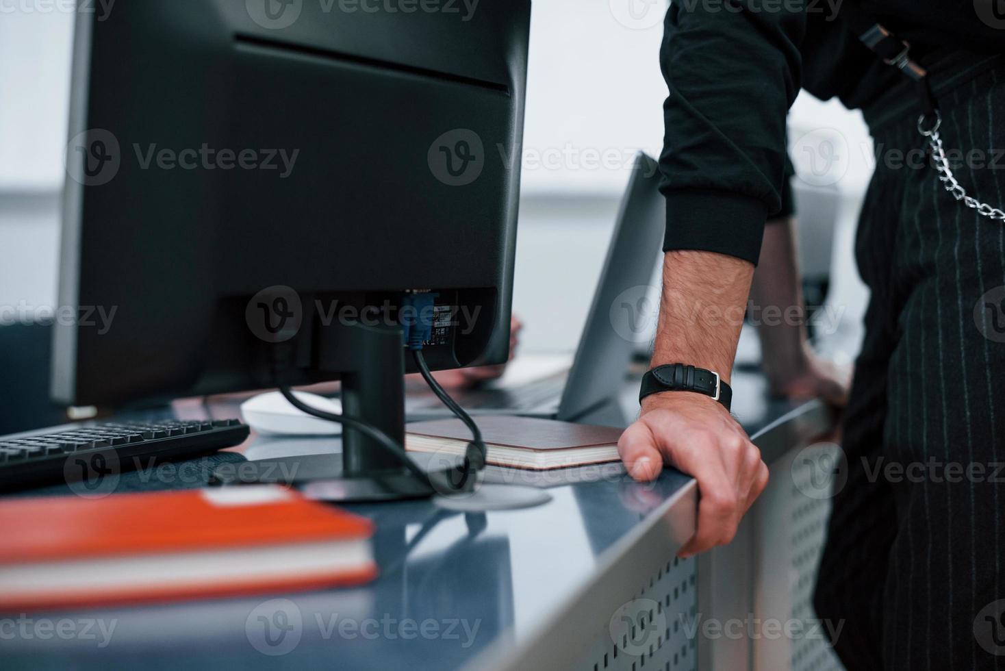 foto ravvicinata di un uomo in abiti ufficiali neri appoggiato al tavolo in ufficio