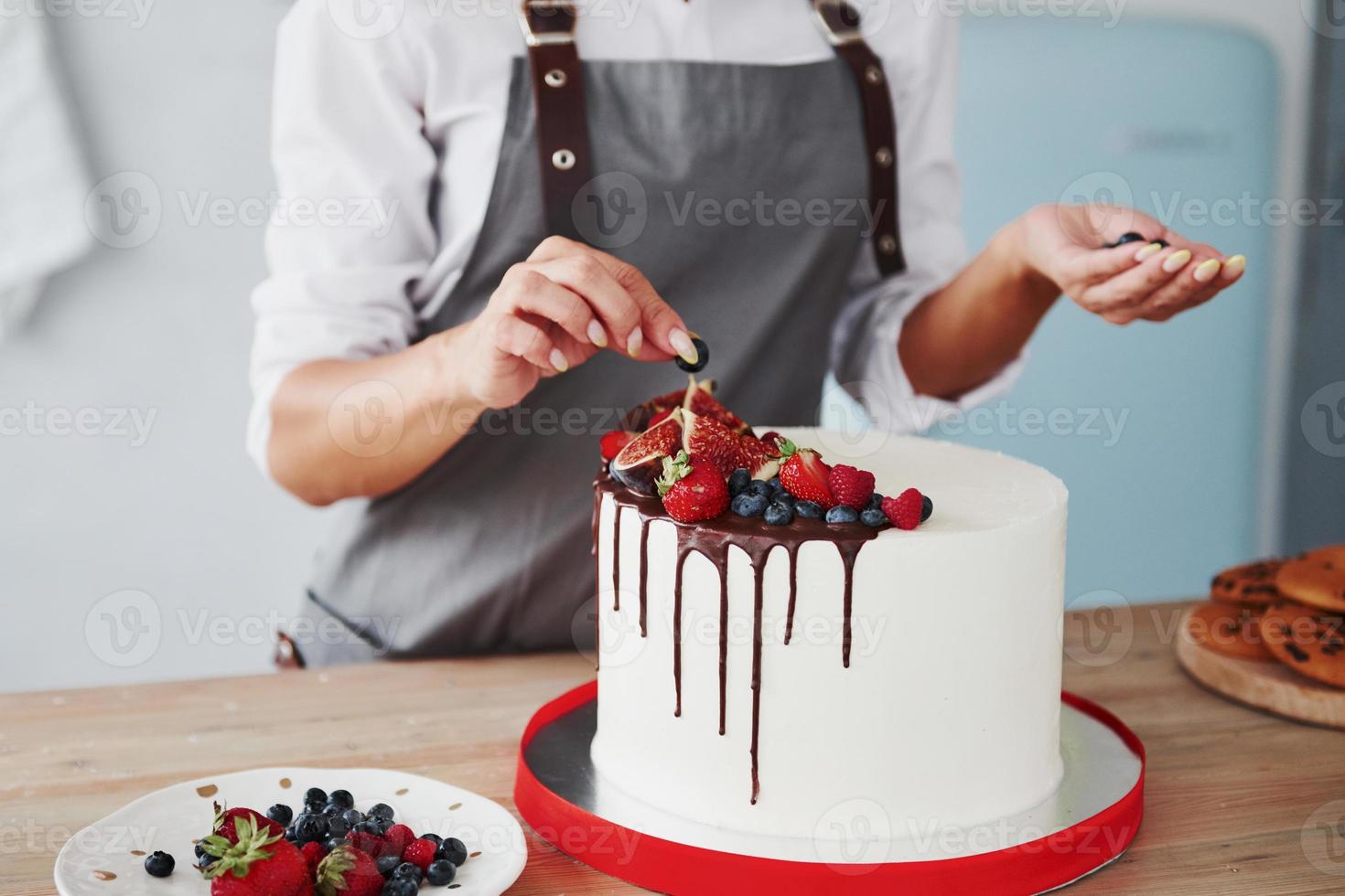 vicino su Visualizza di donna quello mette ciliegie su il dolce torta foto