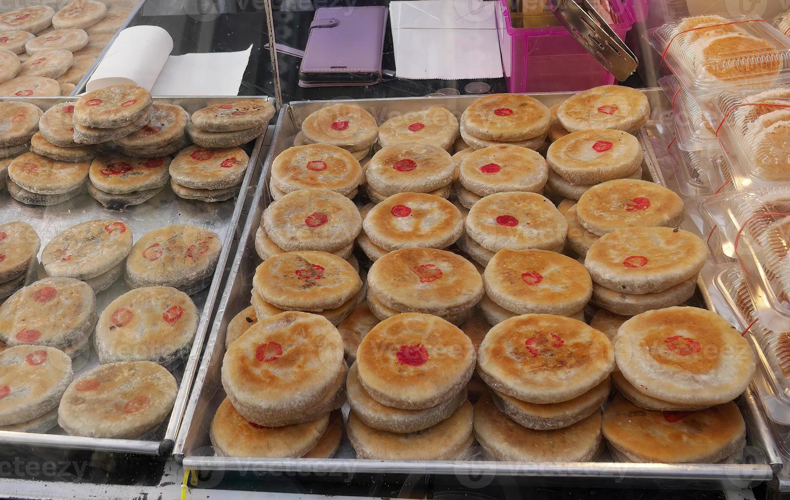 un' mano Tenere pinza al di sopra di il tradizionale Cinese pancake impilamento nel il grande inossidabile vassoio per vendita nel il tailandese strada mercato, dolce merenda, dolce a tailandese strada cibo mercato foto