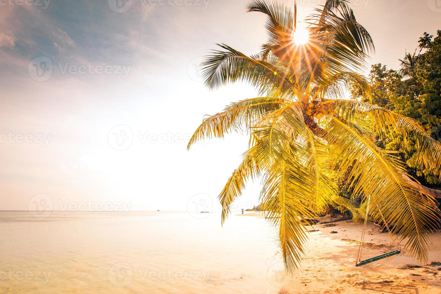 tramonto spiaggia scenario, sorprendente paesaggio e arancia cielo. calma blu mare acqua, nel superficiale laguna con tropicale spiaggia scena, palma albero e un' romantico swing per coppie. spiaggia luna di miele concetto, bandiera foto