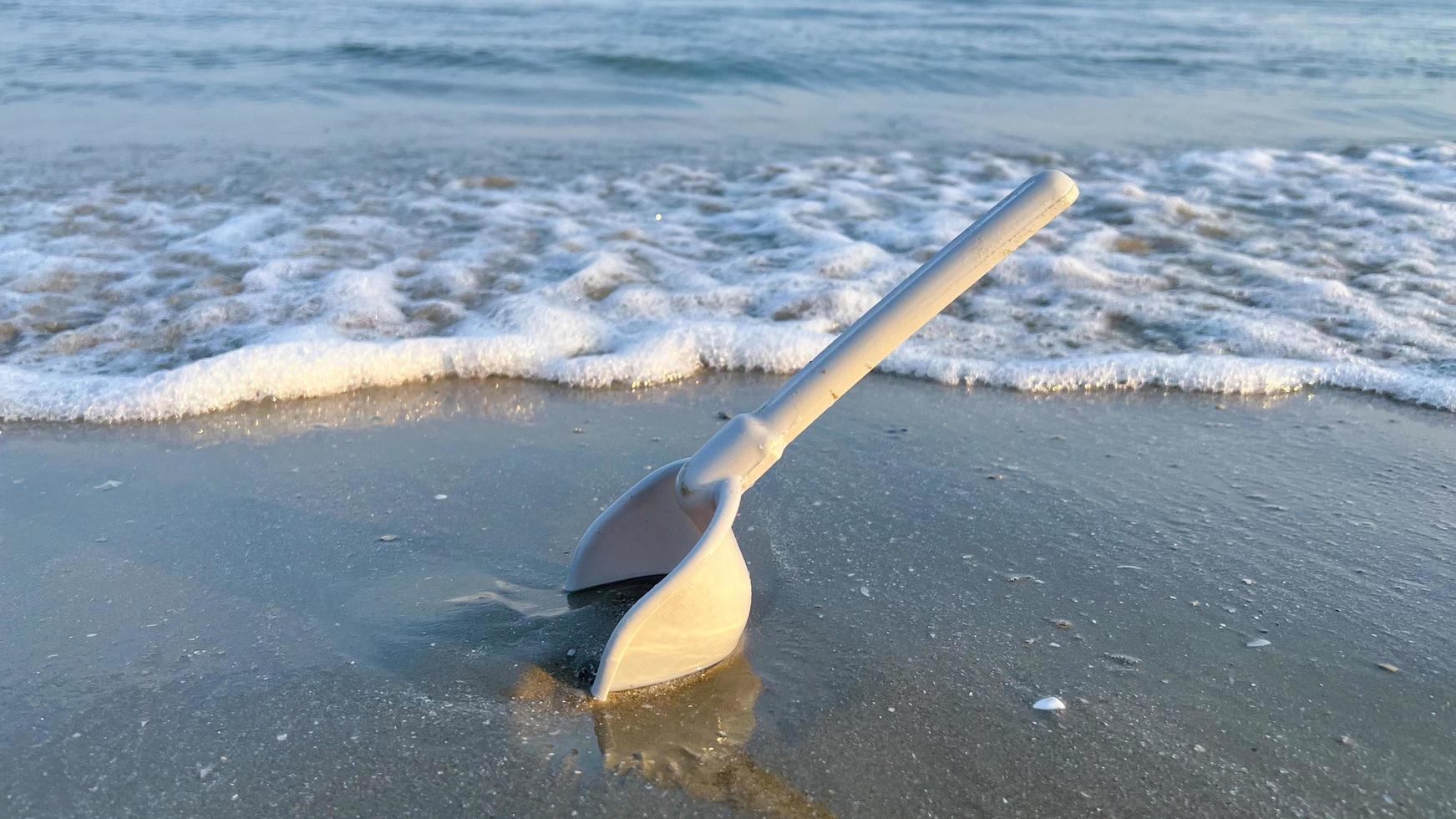 un' spiaggia giocattolo scavare nel il sabbia su il spiaggia foto