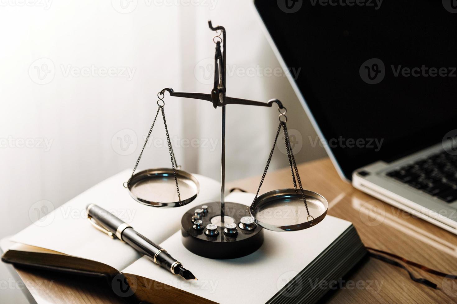 concetto di giustizia e diritto. giudice maschio in un'aula di tribunale con il martelletto, lavorando con computer e tastiera docking, occhiali, sul tavolo alla luce del mattino foto