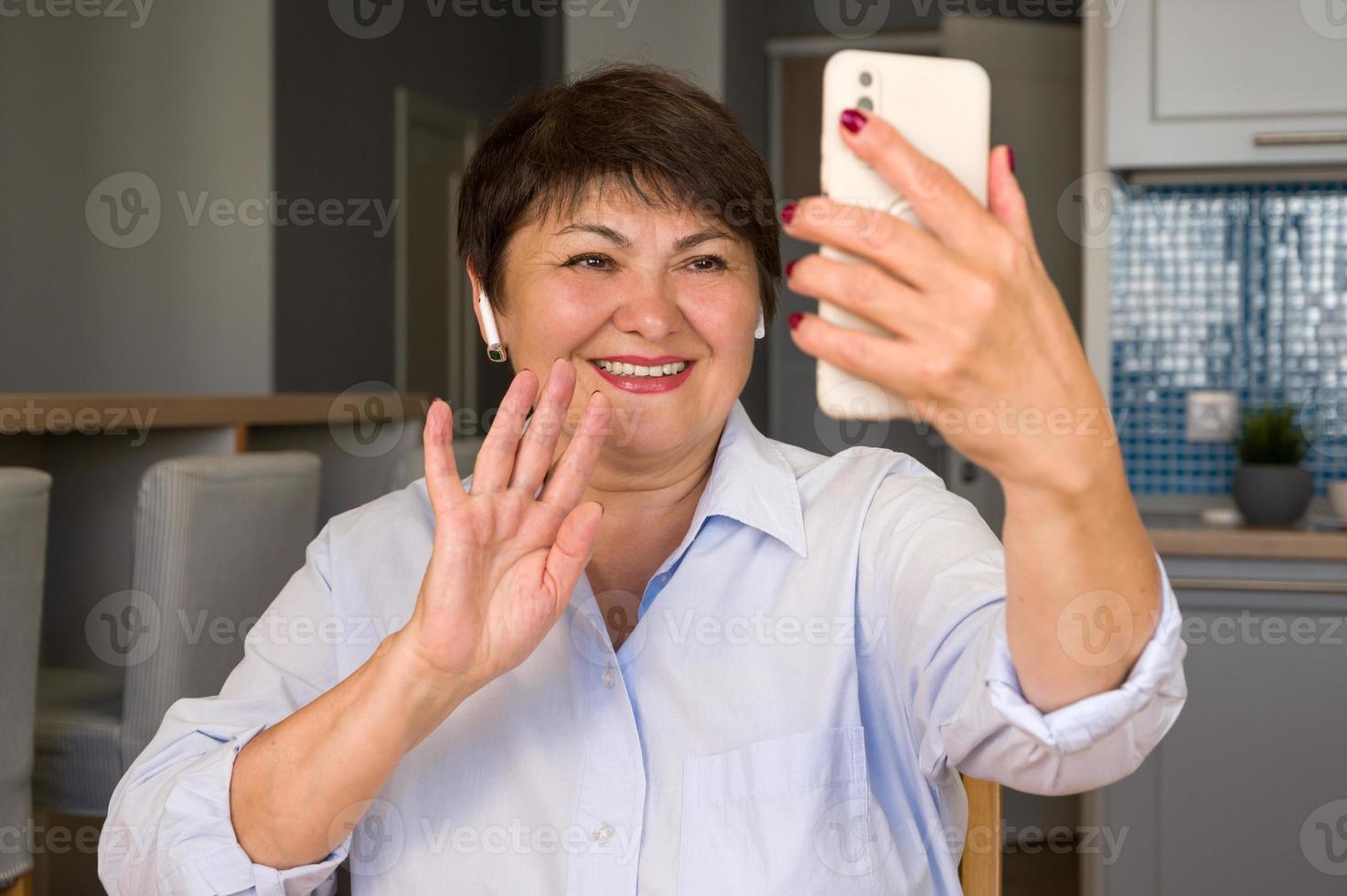 contento Sambuco donna agitando sua mano a Telefono come avendo video chiamata con sua amici, figli, nipoti eccetera. moderno tecnologie uso foto