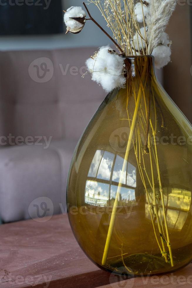 elegante moderno secco fiore preparativi nel un' bicchiere vaso con su Marrone sfondo. foto