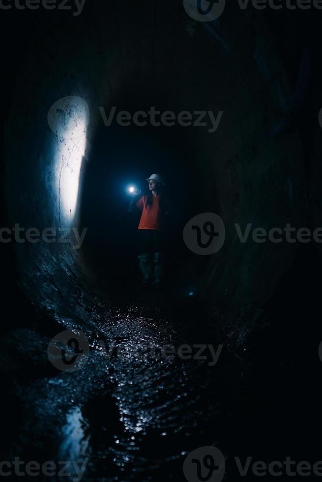 femmina scavatrice con torcia elettrica esplora il tunnel foto