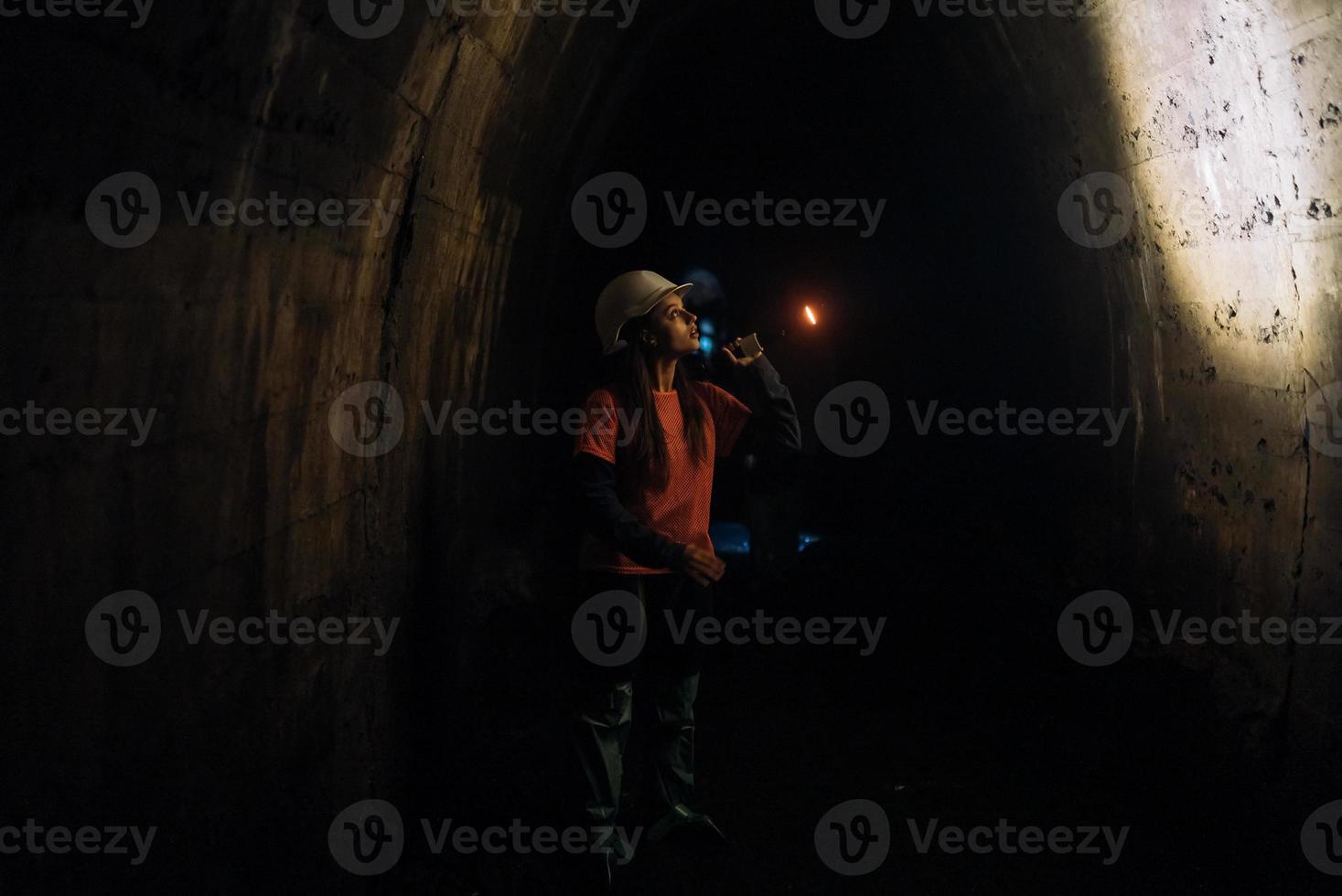 femmina scavatrice con torcia elettrica esplora il tunnel foto