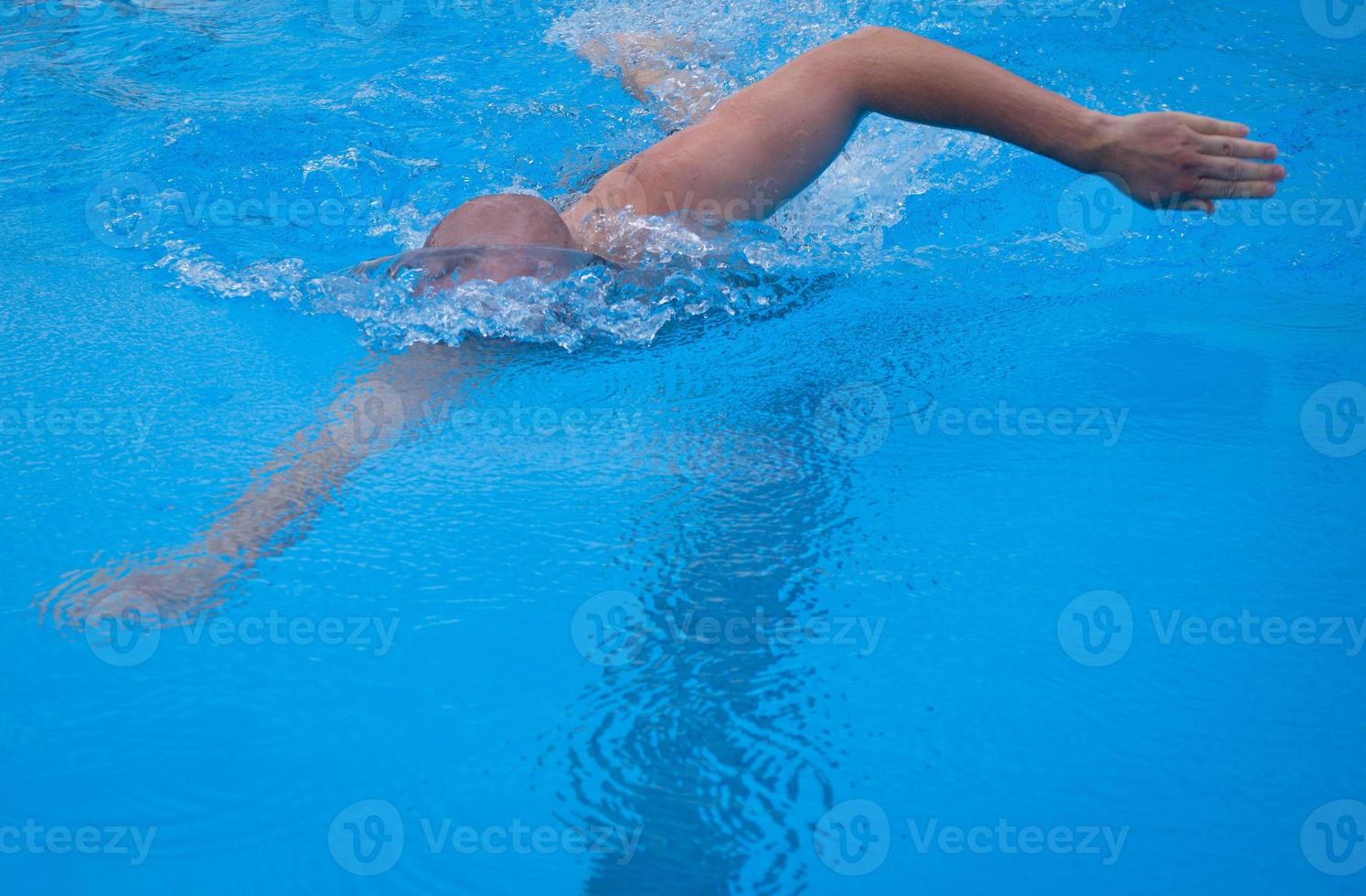 freestyle nuoto nel il nuoto piscina. giovane uomo nuoto il davanti strisciare nel un' piscina. maschio nuotatore pre-strisciare nuoto nel un' piscina. foto